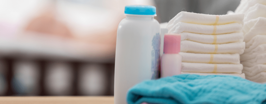A container of baby powder sits by a stack of diapers