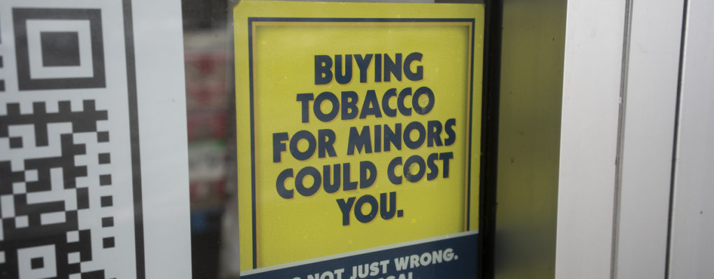 Sign reading 'buying tobacco for minors could cost you.'