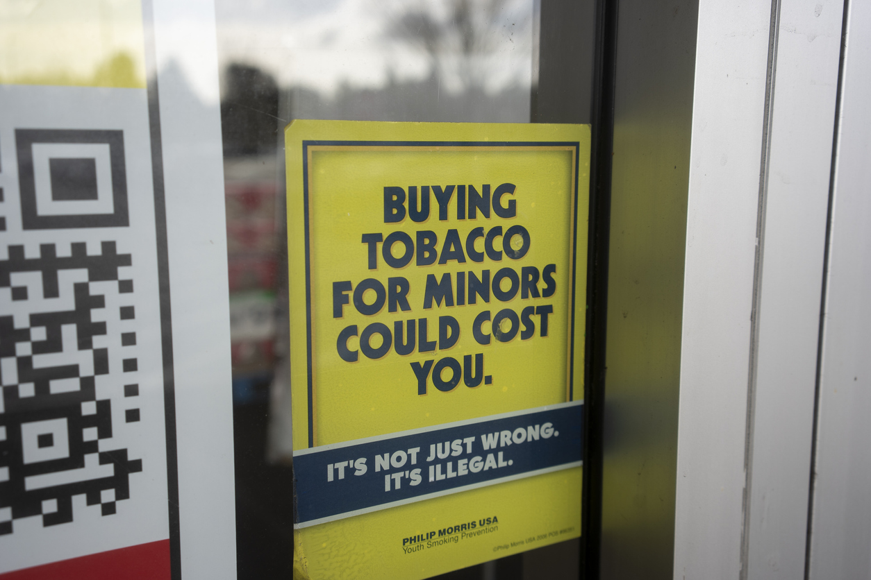 Sign reading 'buying tobacco for minors could cost you.'