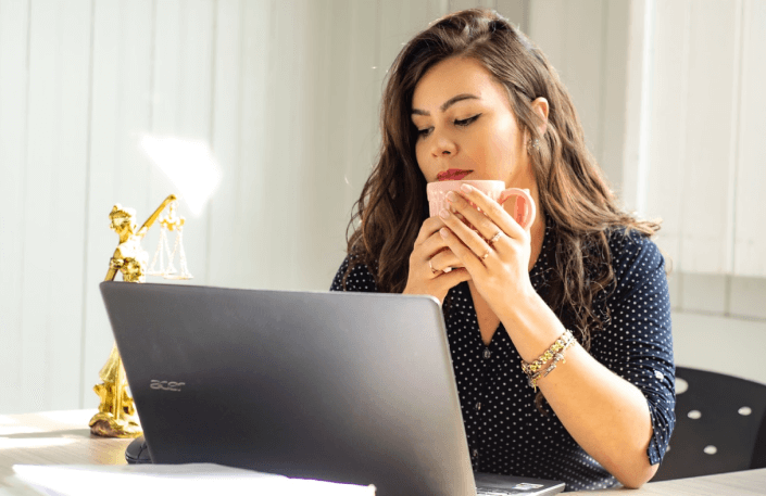 woman holding mug looking at laptop