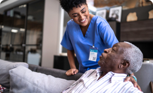 Nurse comforting elderly man sitting on couch