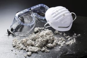 Safety googles and a mask sit near a pile of asbestos dust 