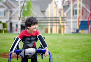 A child with cerebral palsy uses adaptive equipment to walk outside