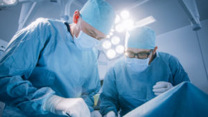 Two doctors perform a surgical procedure on a patient