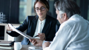 woman with glasses showing a man paperwork