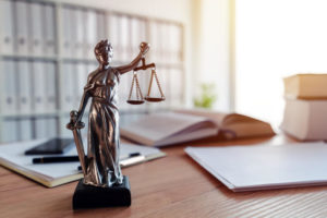 A statue of Lady Justice holding the scales of justice sits on a desk 