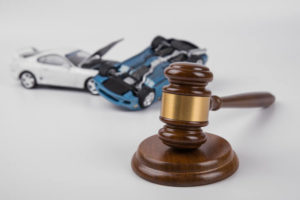 A gavel sits in front of models of two cars that have been in a crash 