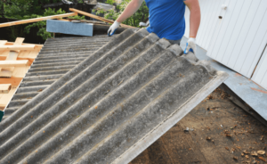 A construction worker handles an asbestos roofing product