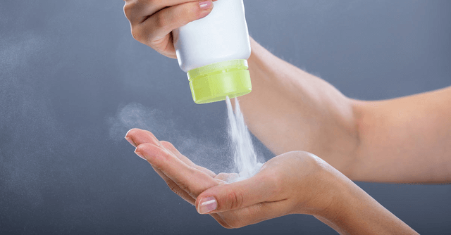 A person squeezes a container of talcum powder for use