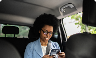a woman sitting in the backseat of a car looking at her cell phone