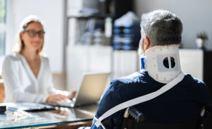 A person in a neck brace meets with a disability denial lawyer.