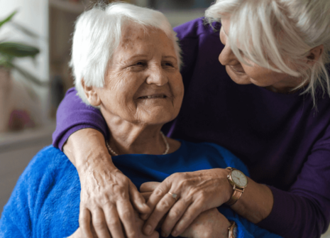 A woman puts her arms around a smiling nursing home resident