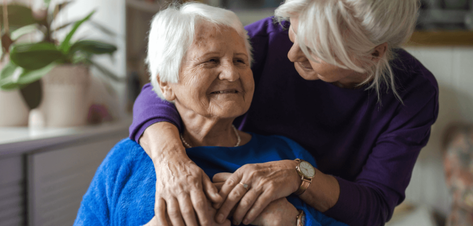 A woman puts her arms around a smiling nursing home resident