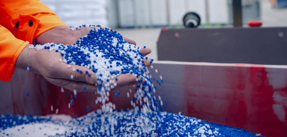 Image of a person holding up blue and white plastic granules representing PFAS chemicals