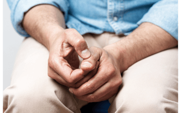 A man clasps his hands in his lap